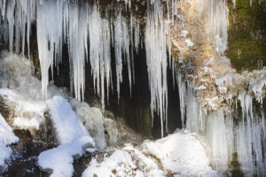 Eiszapfen vor einer Höhlung im Dreimühlen-Wasserfall